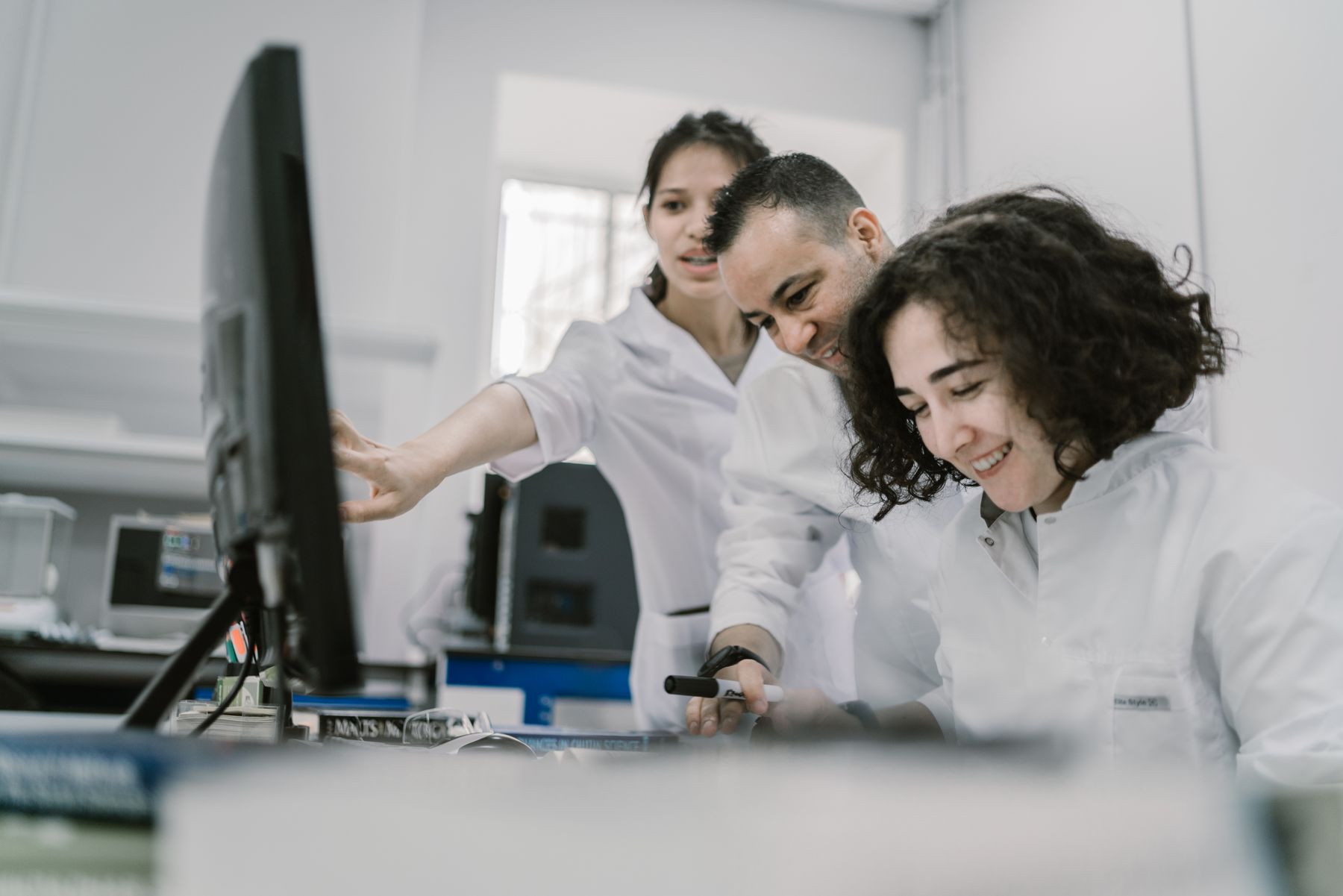 Licensed placeholder photograph showing three scientists smiling as they work together in a laboratory