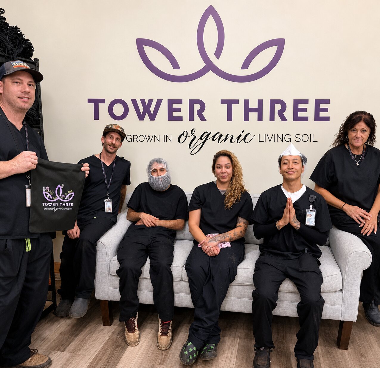 Tower Three team members together beneath the company logo inside their Taunton cultivation facility